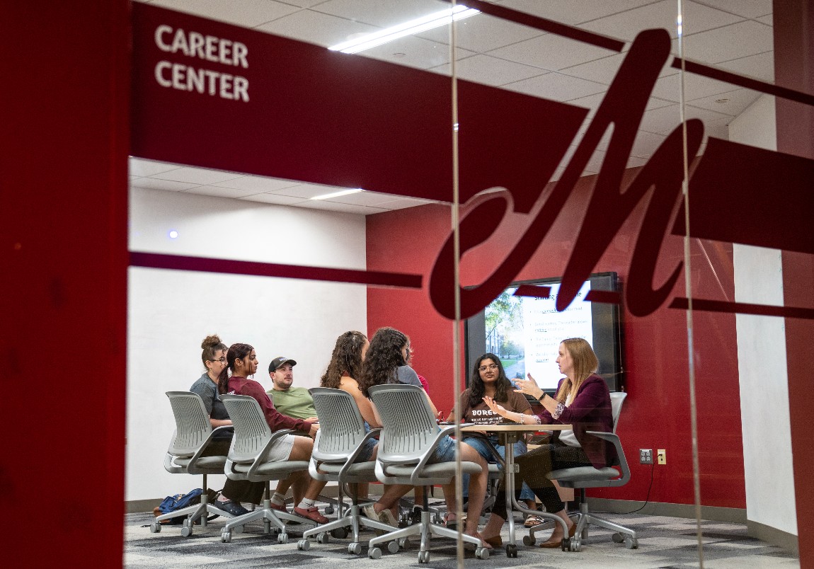 A group of students talk around a table